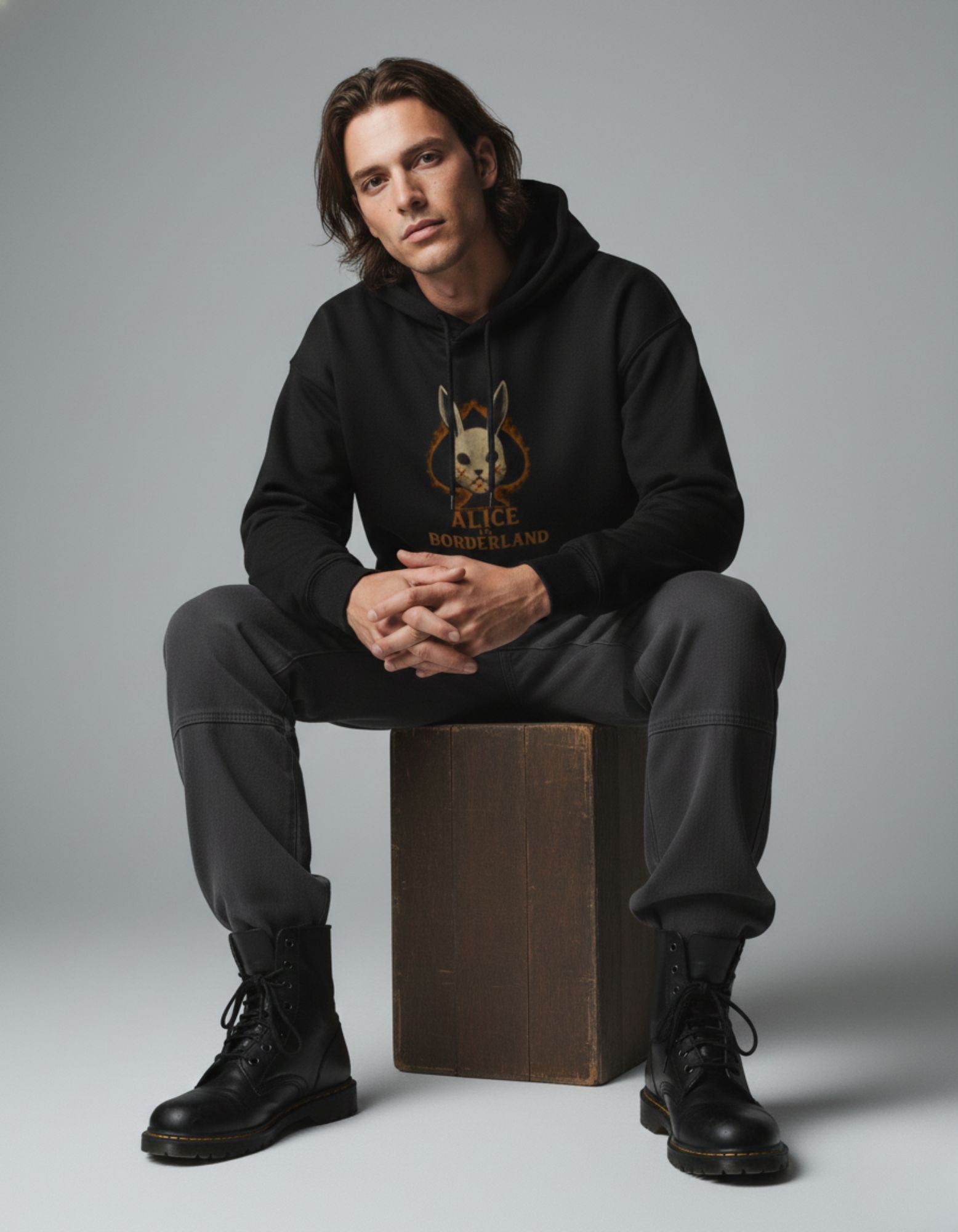 Black oversized hoodie with Alice Borderland graphic worn by male model sitting pose