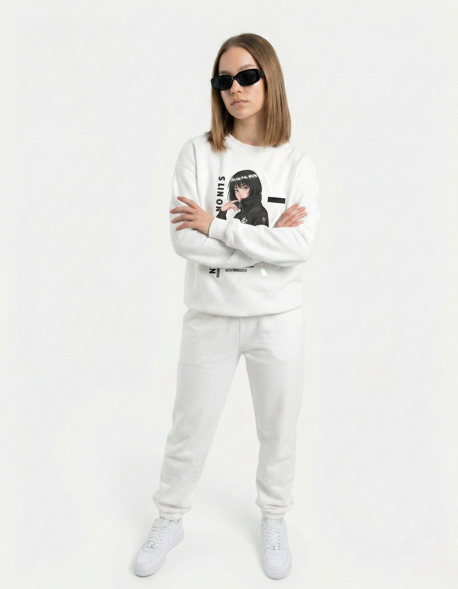 Front view of a model with arms crossed wearing an oversized white anime sweatshirt, capturing a trendy Gen Z urban aesthetic.