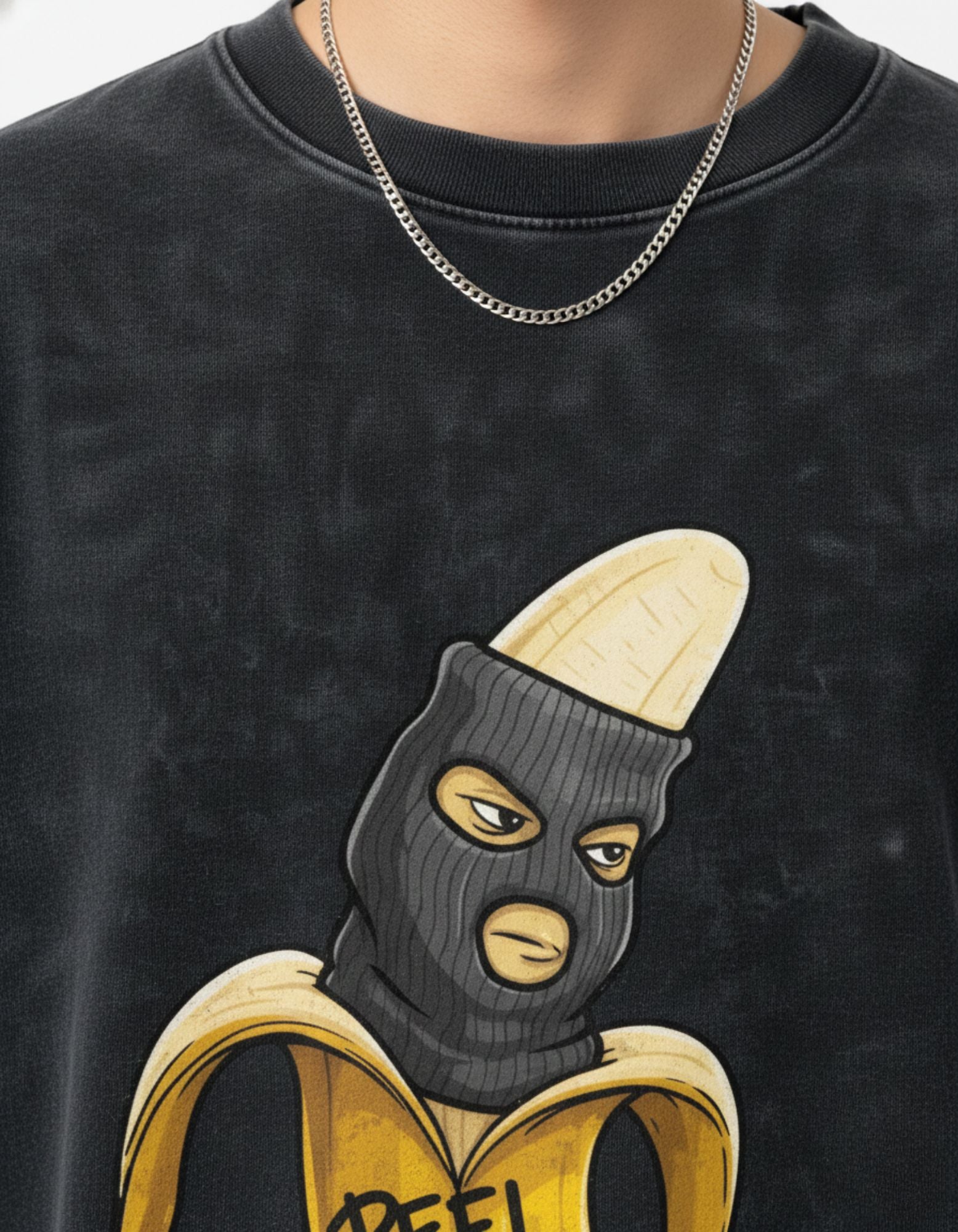 Close-up detail of the high-quality 240 GSM 'Peel Fast Die Young' banana mask graphic print on a charcoal t-shirt.