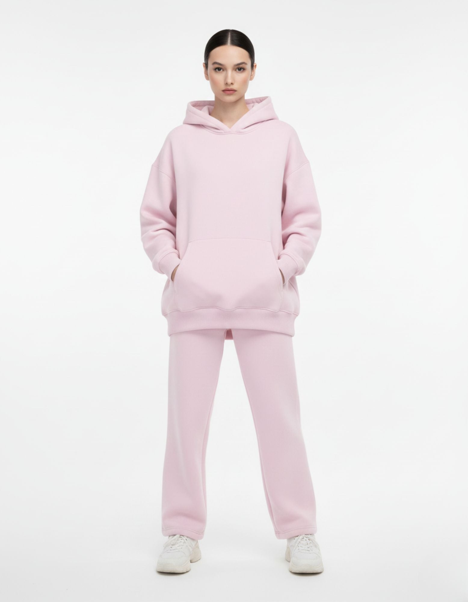 Front view of a model wearing a heavyweight light pink oversized hoodie with matching sweatpants from a Gen Z streetwear brand.