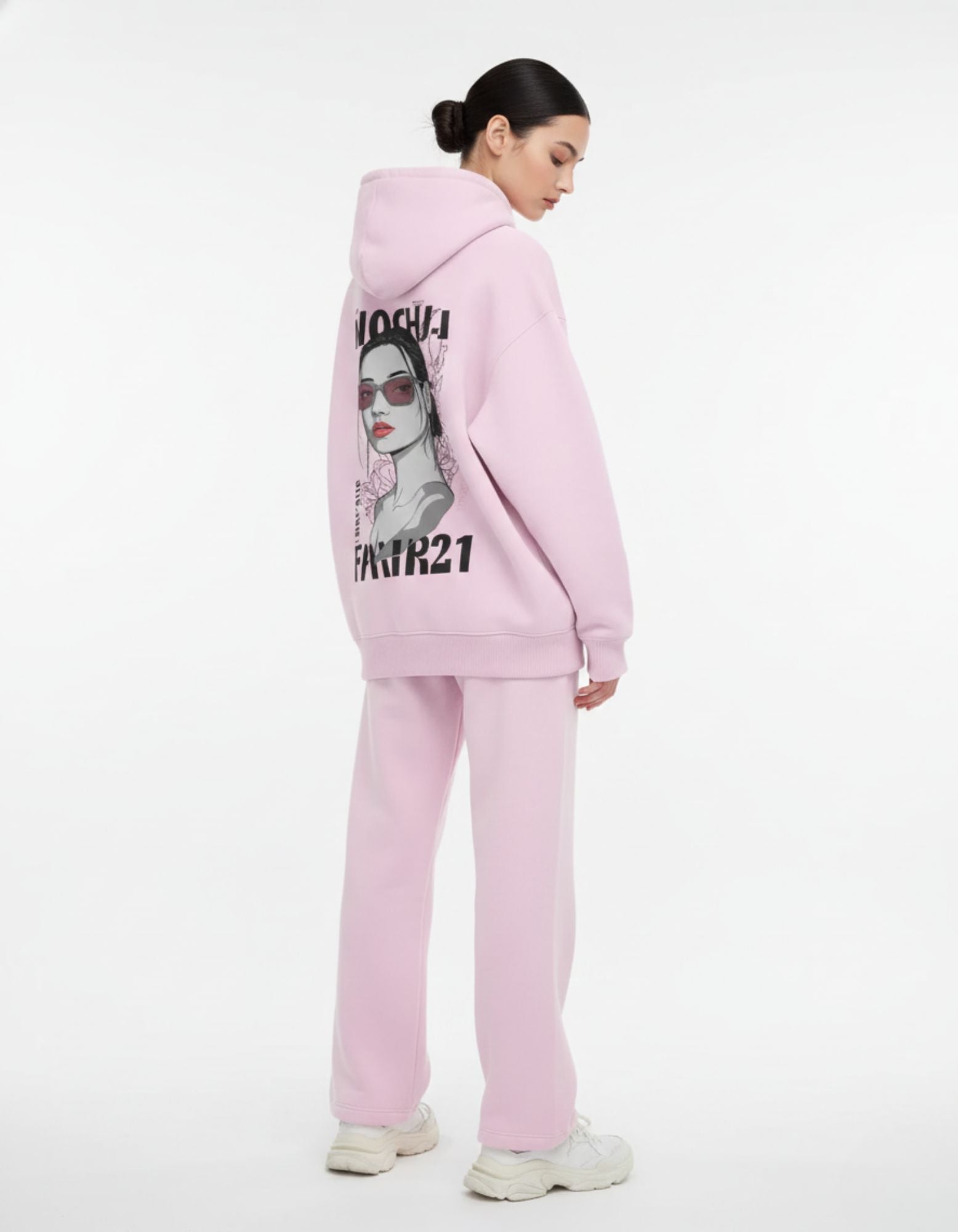 Side profile of a model in a light pink oversized tracksuit set, highlighting the baggy aesthetic and high-quality fabric.