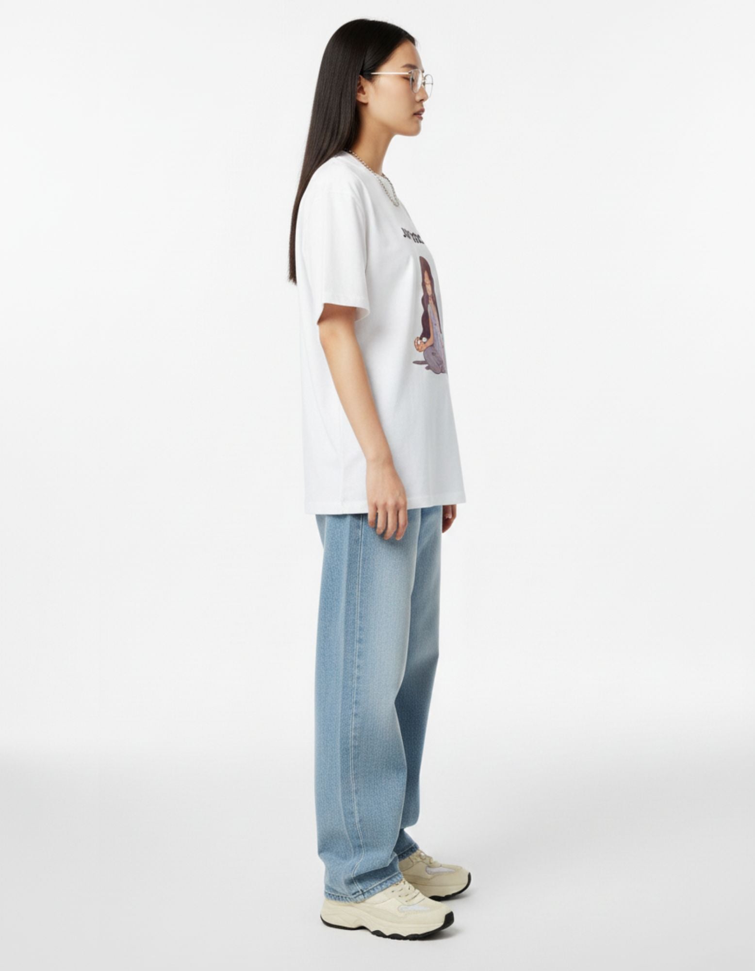 Side profile of woman in white boxy fit yoga graphic t-shirt showing drop shoulder design.