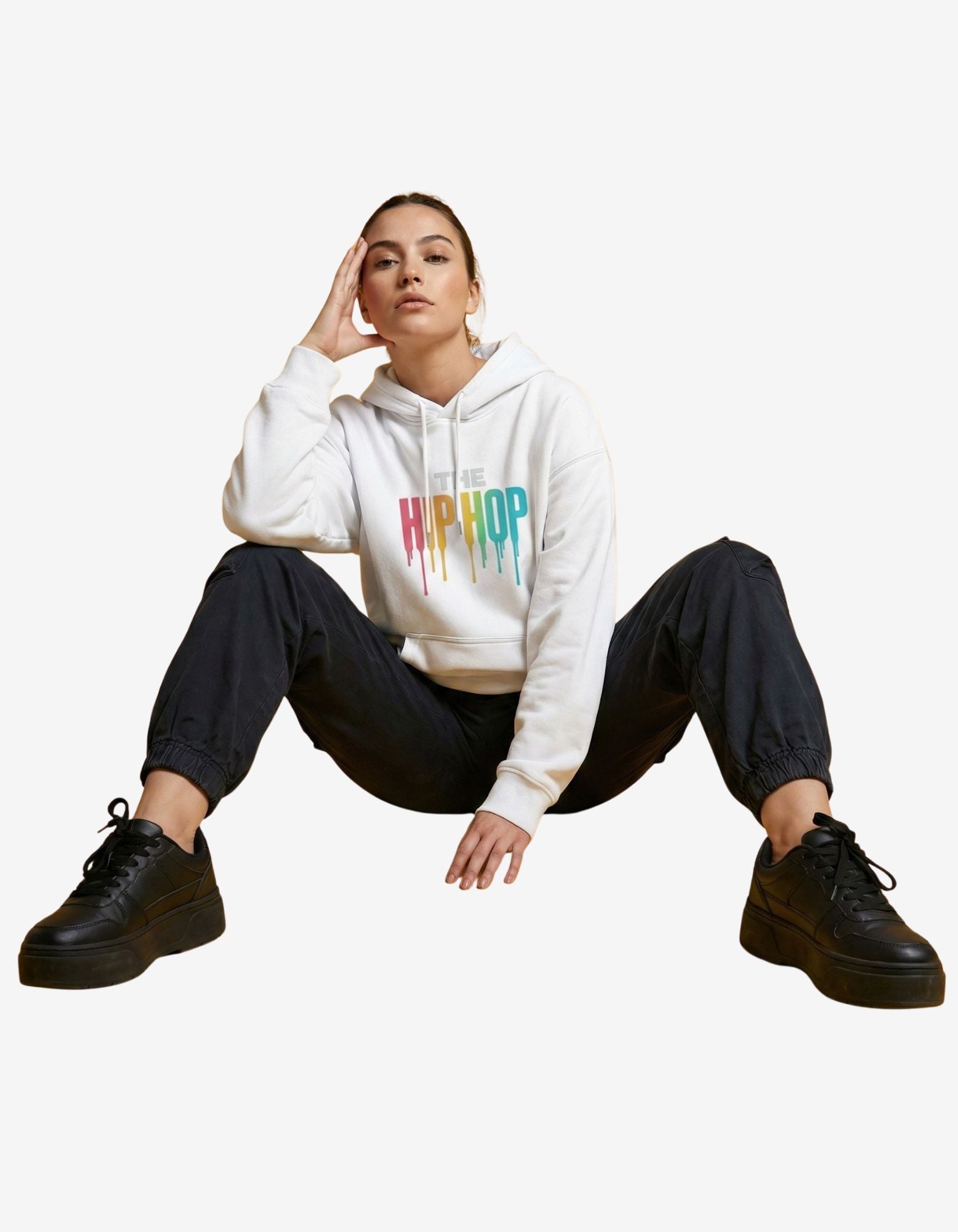 Lifestyle shot of a model in a white "THE HIP HOP" hoodie and black joggers, highlighting a casual Gen Z streetwear vibe.