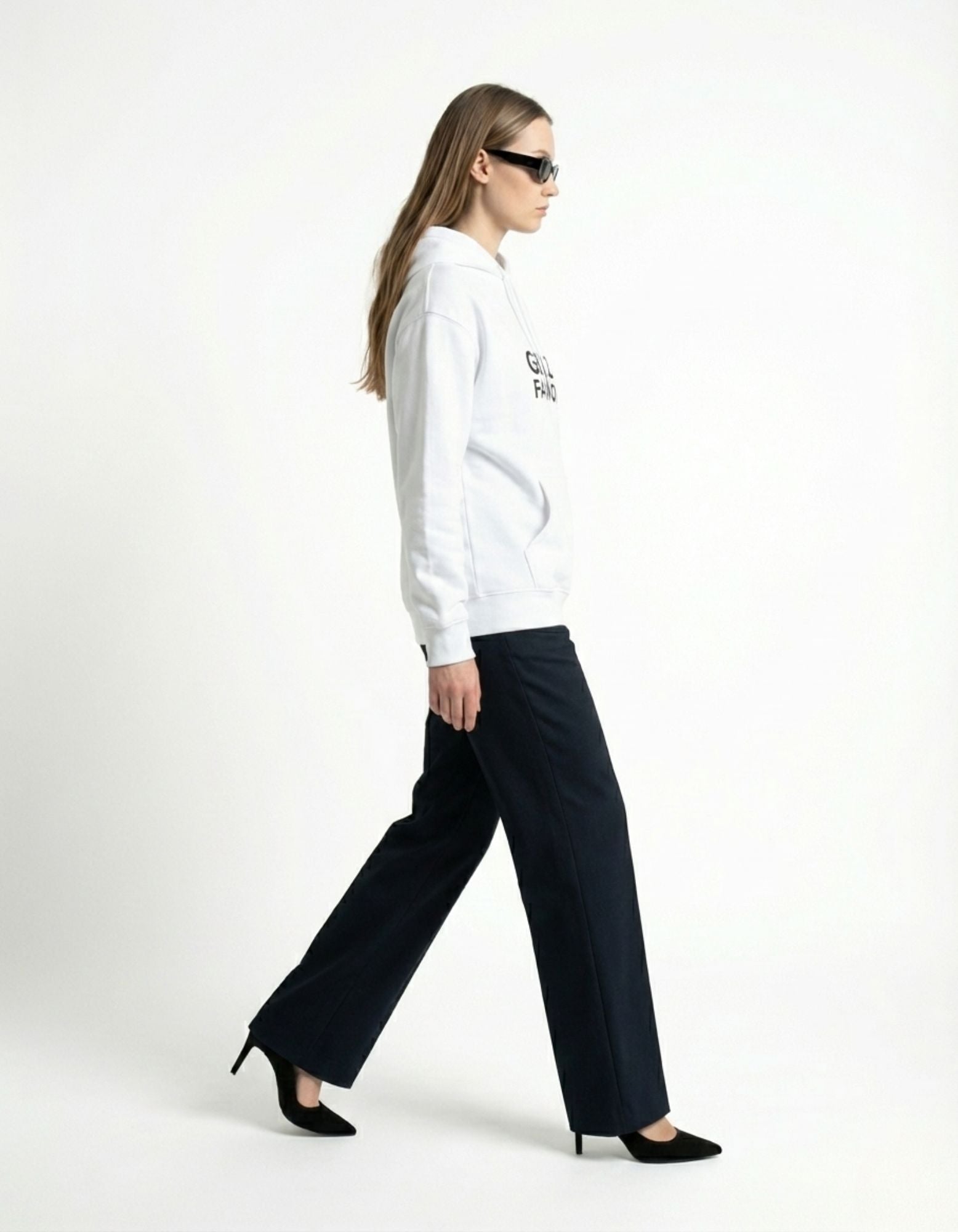 Woman wearing a white GENZs FASHION hoodie with black trousers and a black leather handbag.