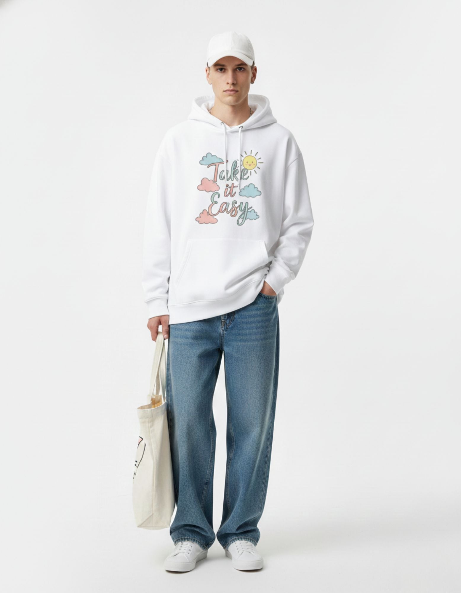 Male model standing with a tote bag wearing a white aesthetic cloud hoodie and baggy jeans for a casual look.