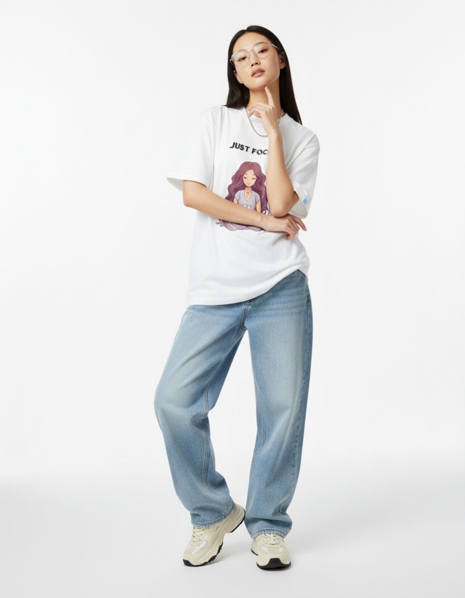 Woman wearing white oversized meditation t-shirt with "Just Focus" yoga graphic print.