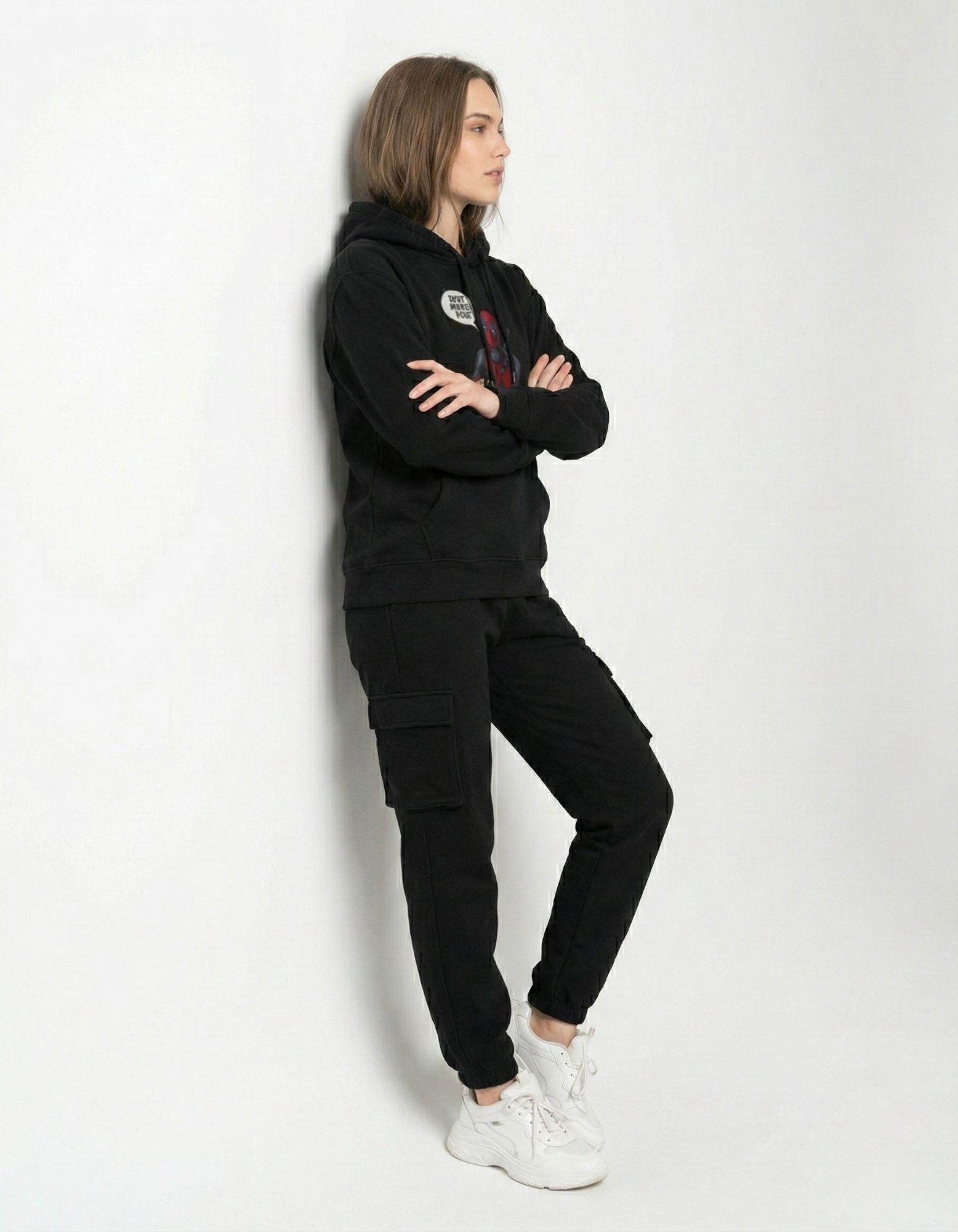 Side profile of a woman wearing a black Deadpool movie hoodie with cargo pants, ideal for urban street style.