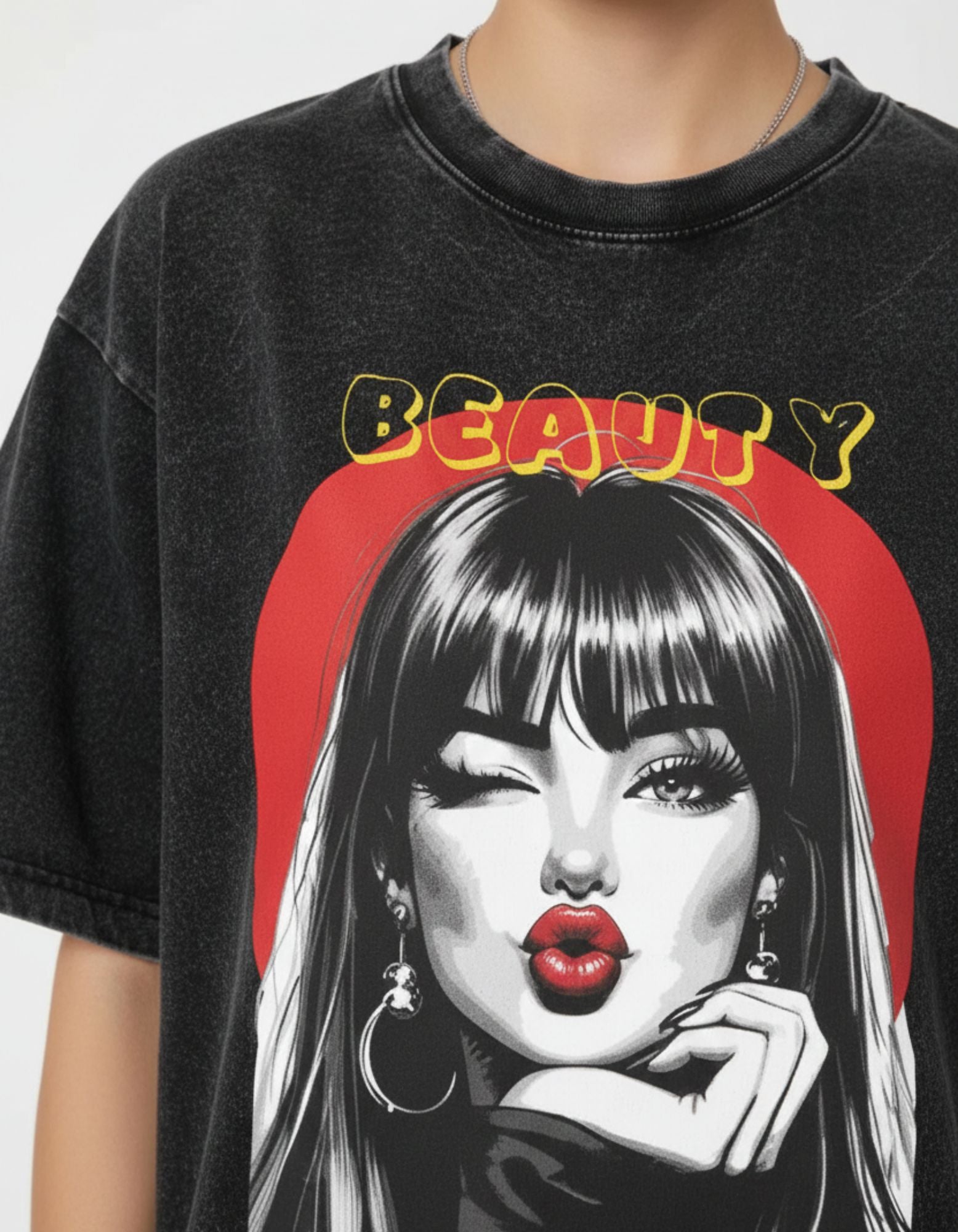 Close-up detail of the 'Beauty' graphic print on a charcoal oversized t-shirt featuring a retro winking girl illustration.