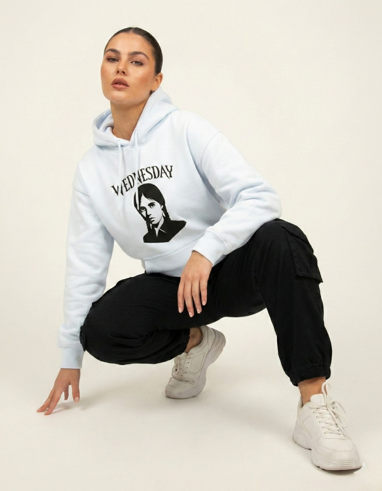 Model posing in a pastel blue Wednesday Addams graphic hoodie, capturing a modern gothic streetwear aesthetic.