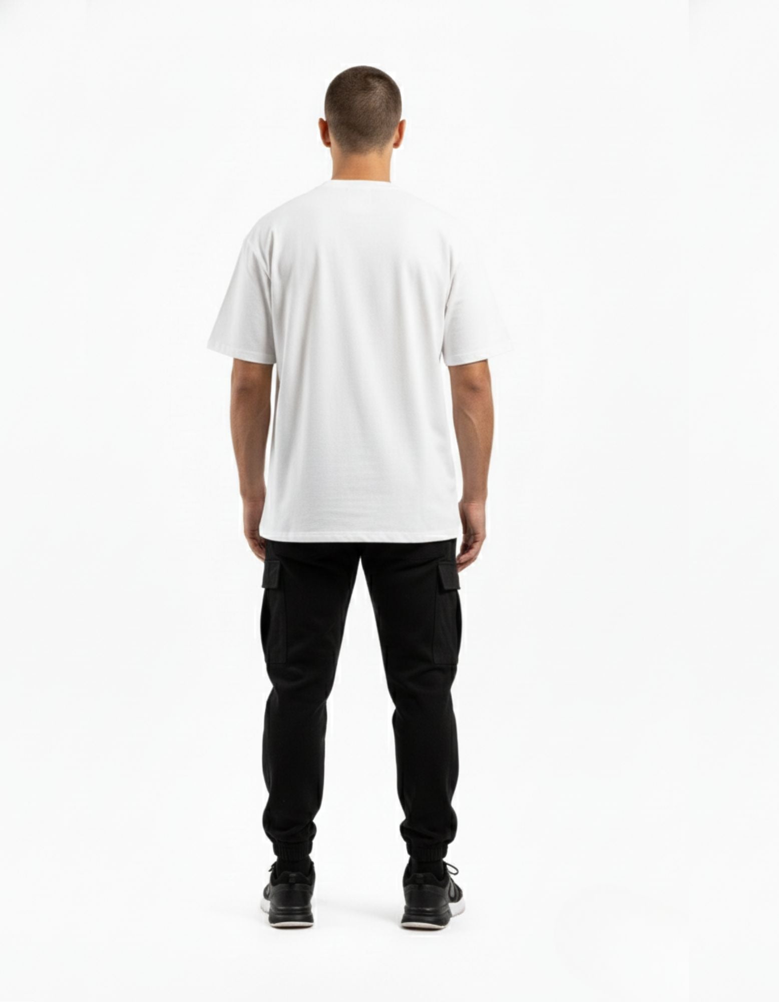 Back view of men's white oversized t-shirt with a relaxed streetwear fit, styled with black cargo joggers.
