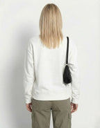 Rear view of a model in a white relaxed-fit crewneck sweatshirt and olive green cargo trousers, highlighting the clean silhouette.