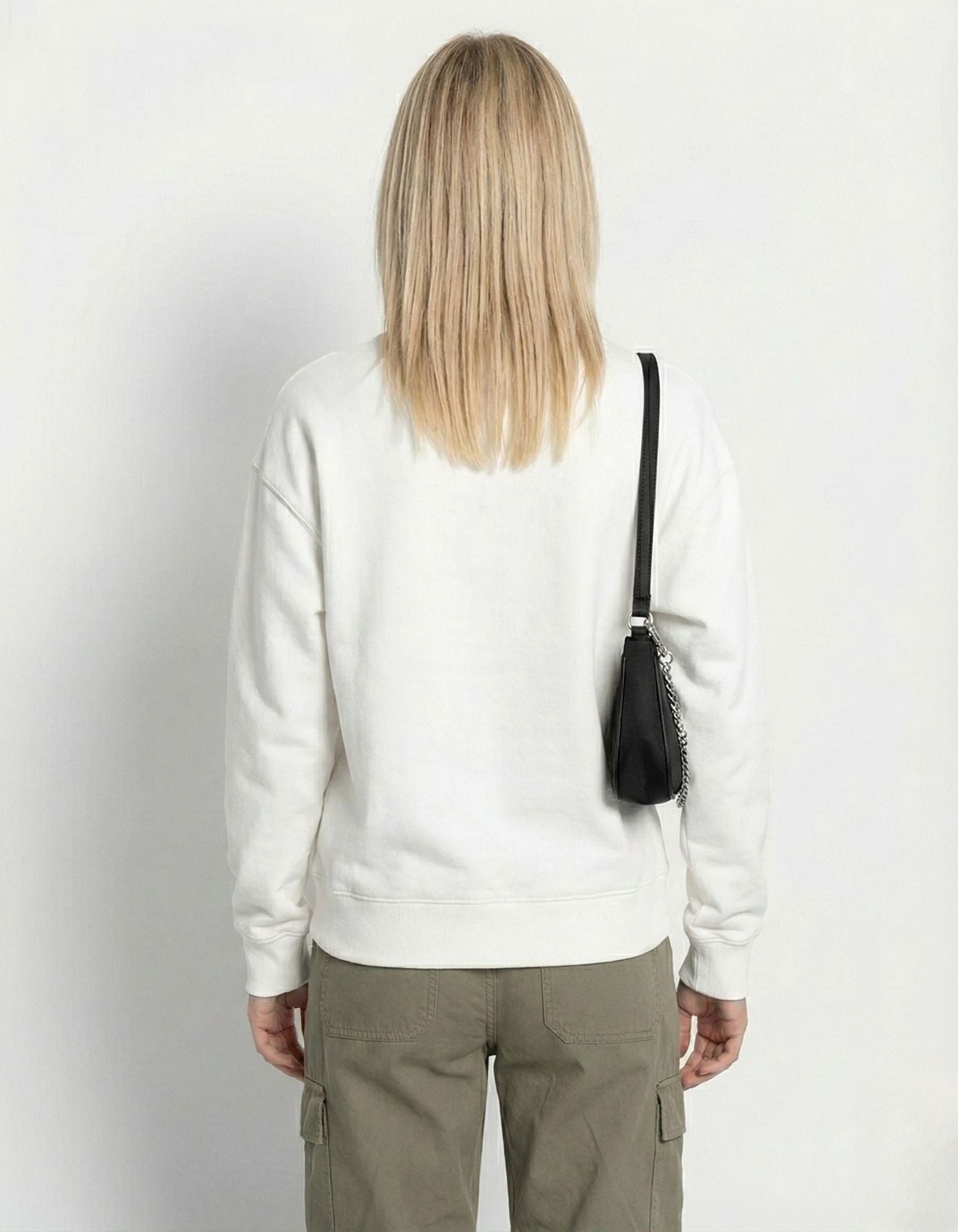 Rear view of a model in a white relaxed-fit crewneck sweatshirt and olive green cargo trousers, highlighting the clean silhouette.