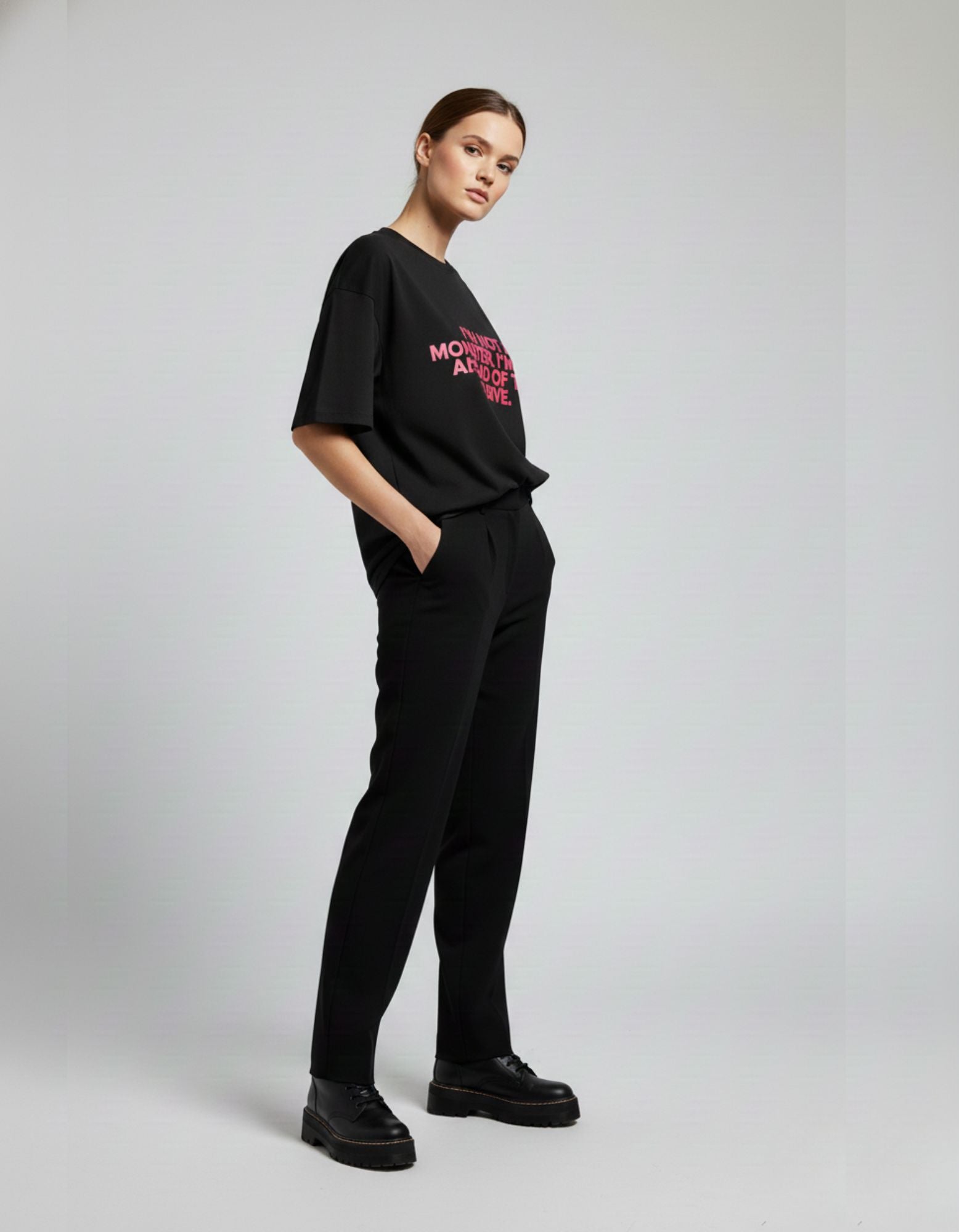 Side view of woman in black oversized t-shirt with pink typography, a trendy streetwear essential in India 2025.