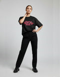 Woman wearing black oversized slogan t-shirt with pink text "I'm Not A Monster" in Indian streetwear style.
