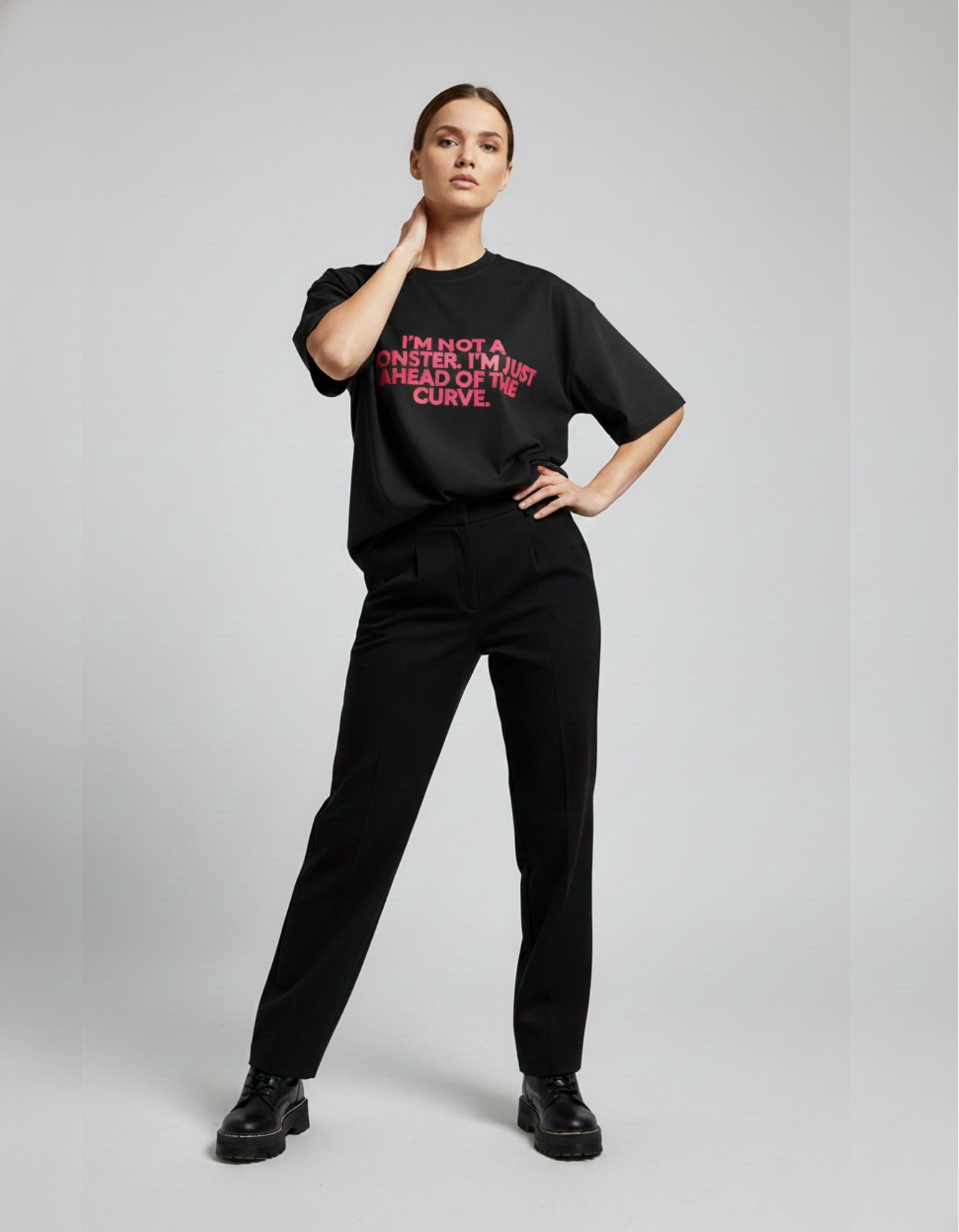 Woman wearing black oversized slogan t-shirt with pink text "I'm Not A Monster" in Indian streetwear style.