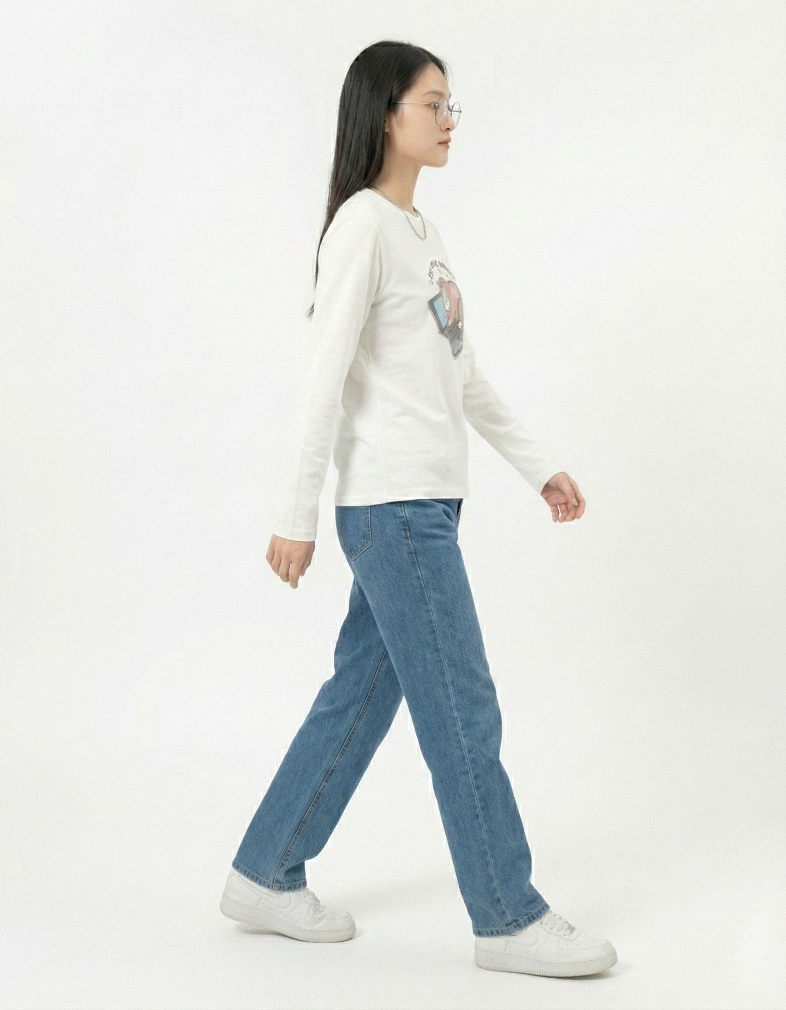 Side profile of a woman walking in a GENZs Fashion white long-sleeve cat graphic top, showing the movement and comfortable fit of the fabric.