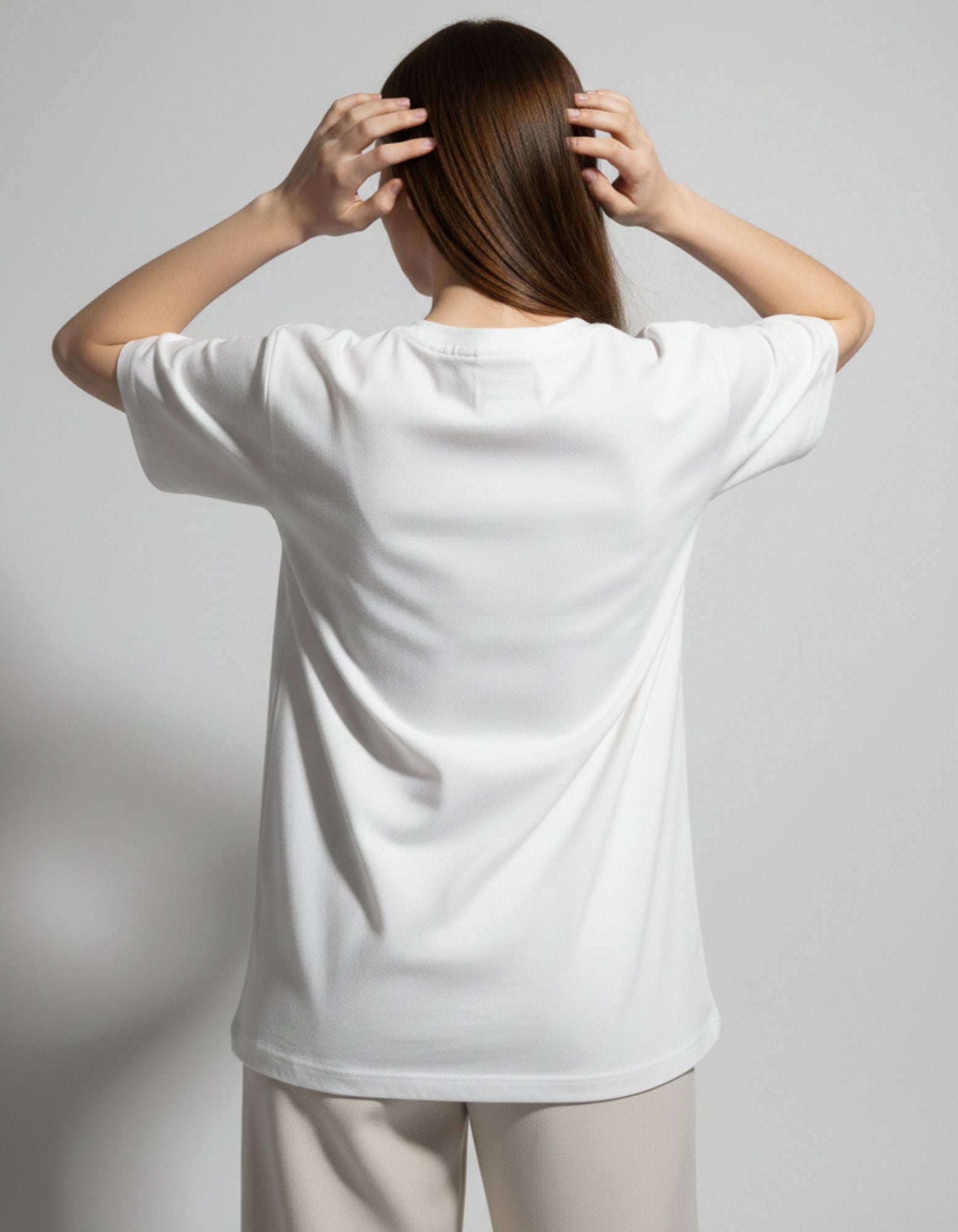 Back view of a white oversized drop-shoulder t-shirt for women, showing the relaxed streetwear silhouette.