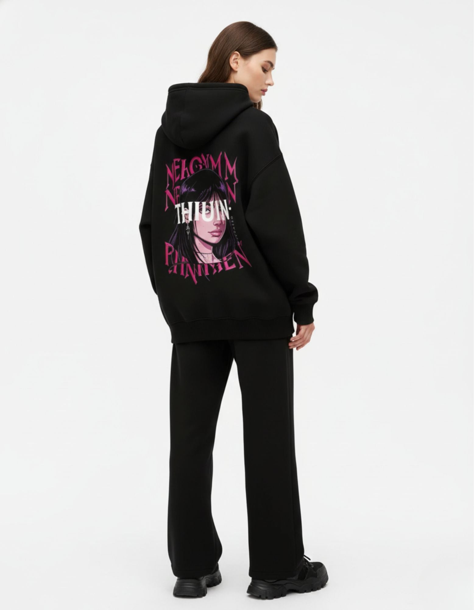 Full back view of a woman wearing an oversized black anime girl graphic hoodie paired with black wide-leg trousers for a streetwear look.