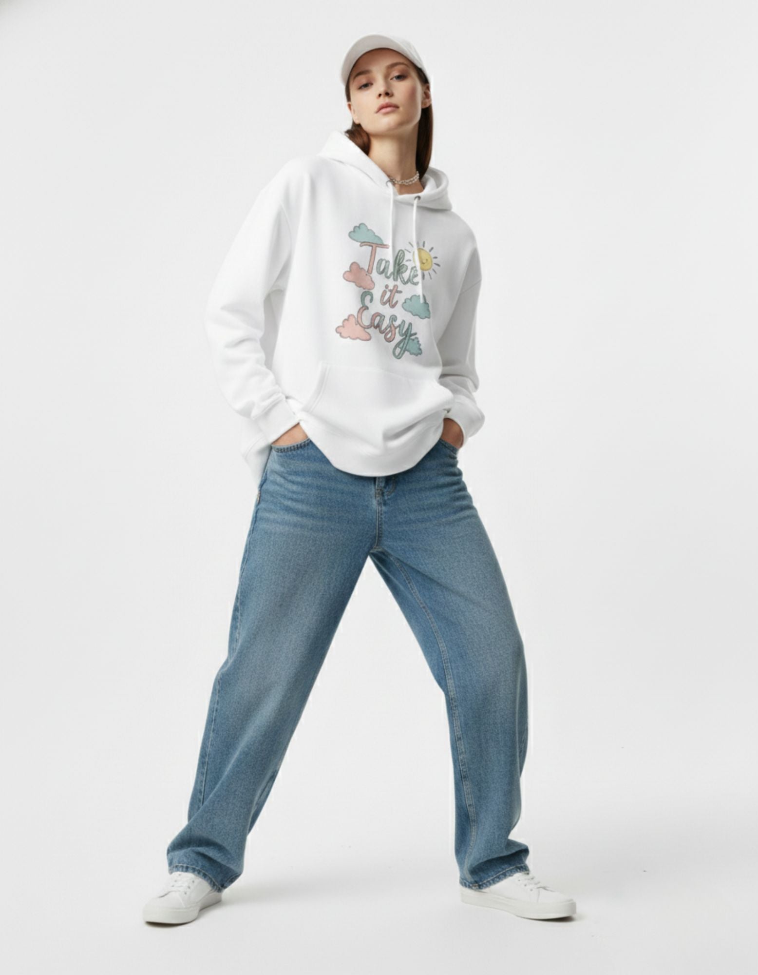 Female model in a white graphic hoodie with a "Take it Easy" cloud design and white baseball cap, Gen Z style.