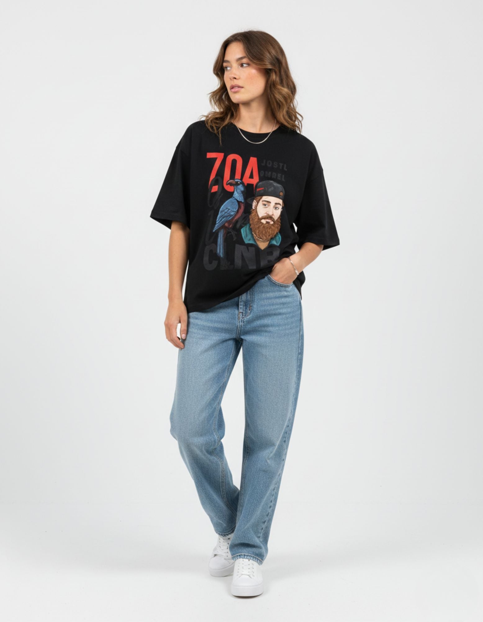 Female model wearing a relaxed-fit black oversized tee with a blue bird and '704' graphic detail.