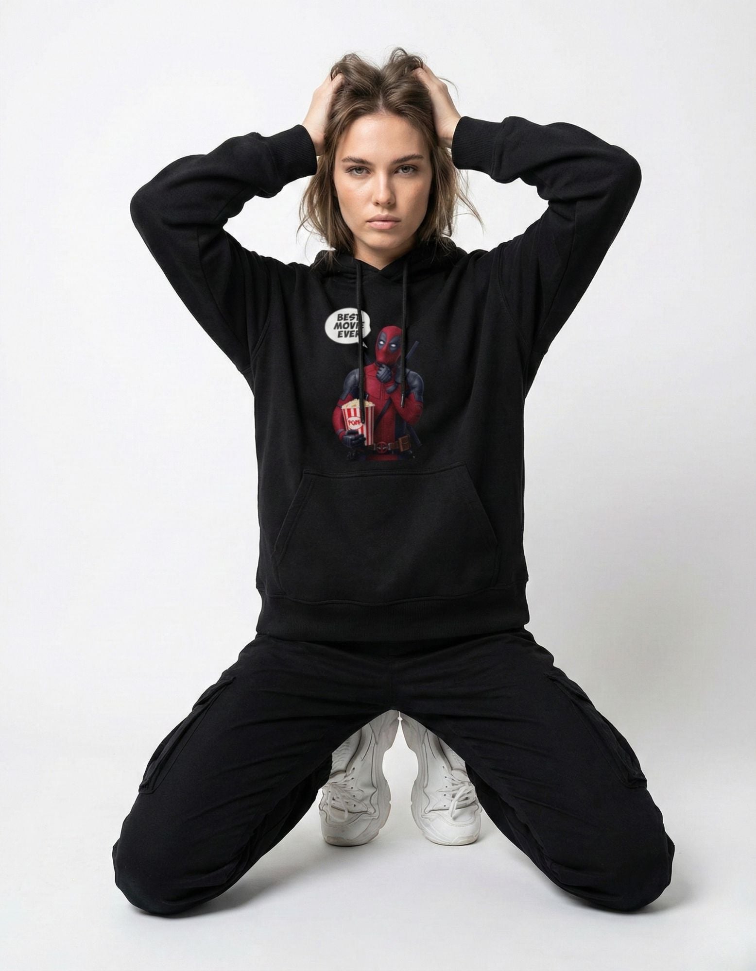 A woman posing in a black Deadpool graphic hoodie for Gen Z streetwear fashion.