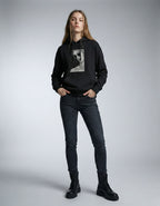 Full front view of a woman in a black GENZs Fashion graphic hoodie, styled with black boots and denim.