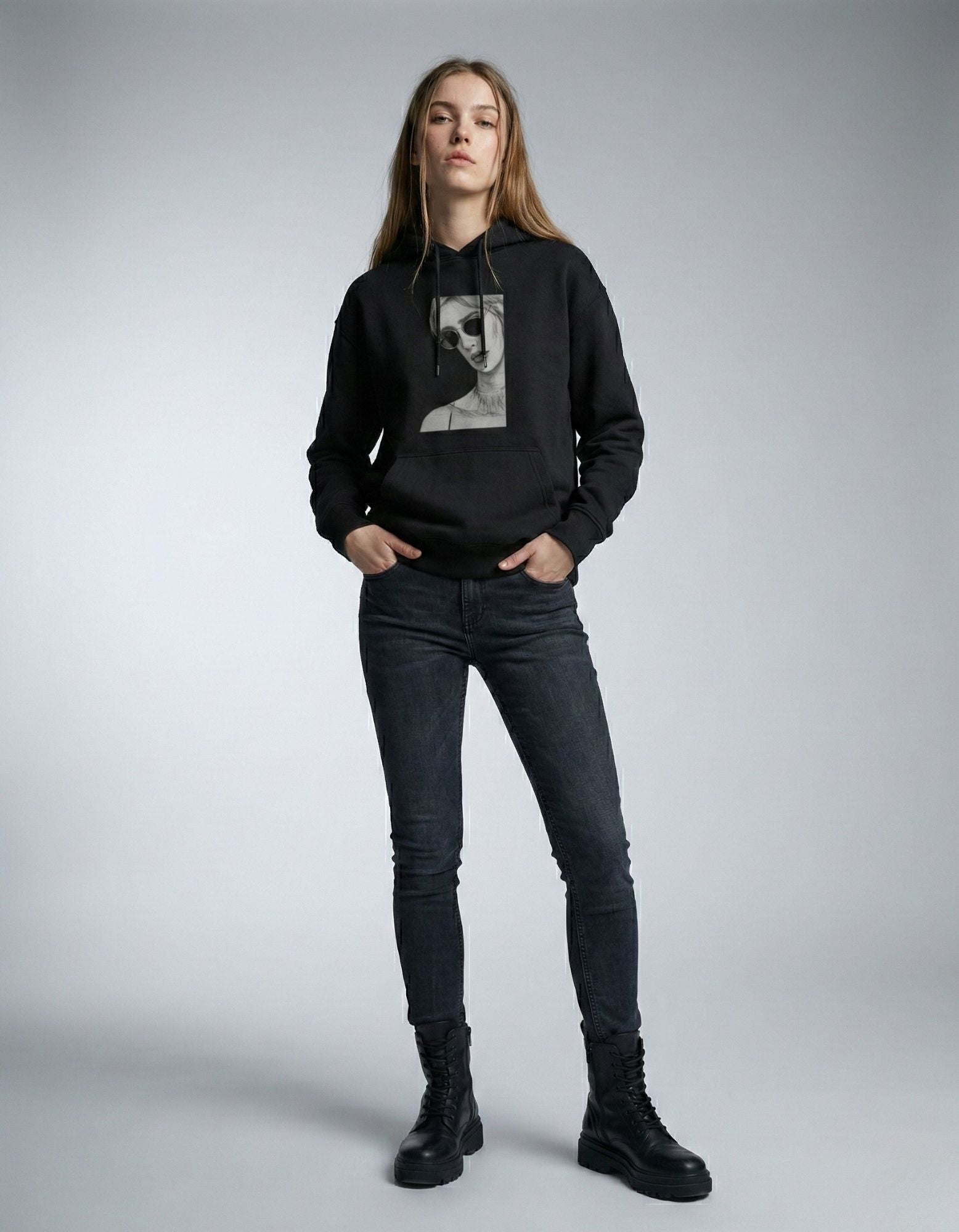 Full front view of a woman in a black GENZs Fashion graphic hoodie, styled with black boots and denim.