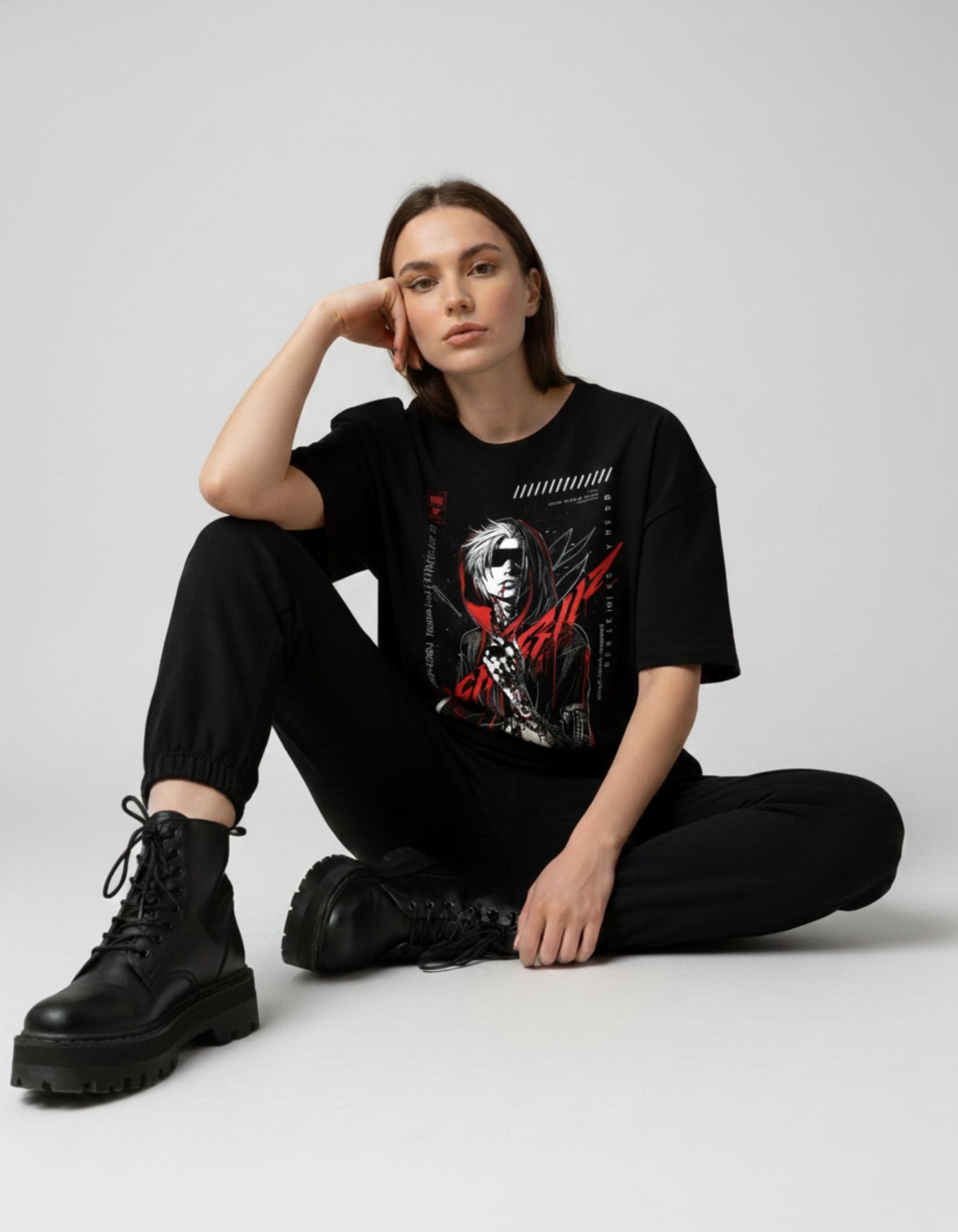 Female model posing in a black oversized anime graphic t-shirt paired with black joggers and combat boots for a grunge look.