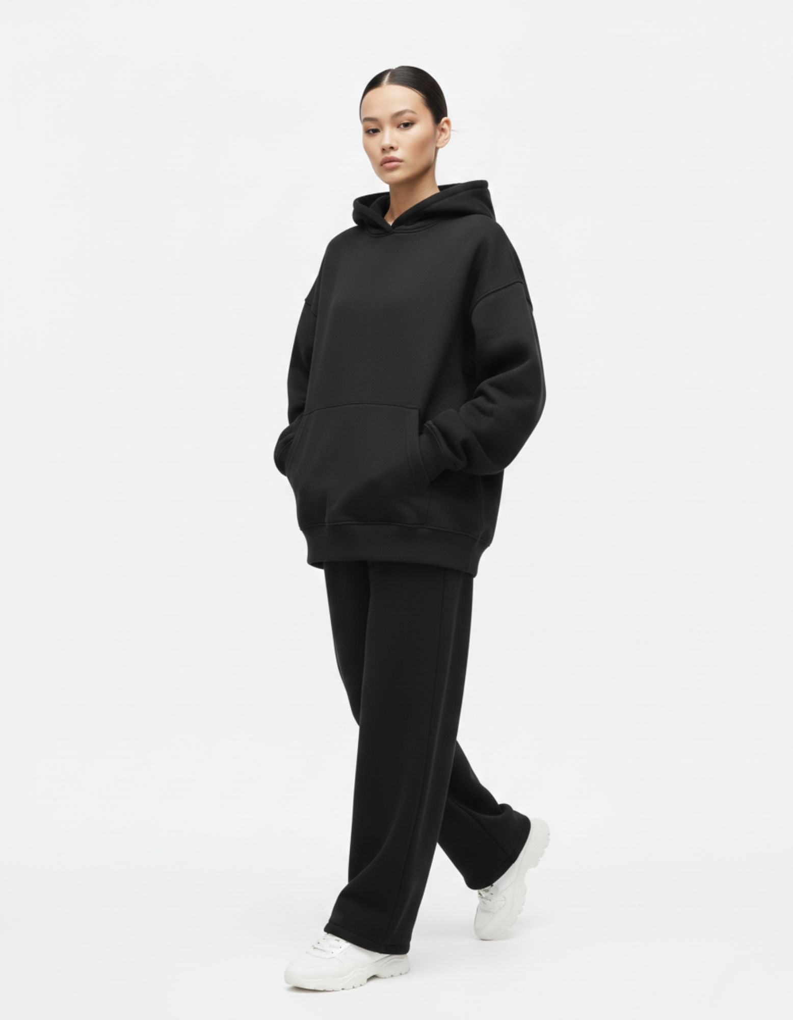 "A female model wearing a GENZs Fashion oversized black hoodie and matching joggers, showcasing a minimalist Gen Z streetwear aesthetic."