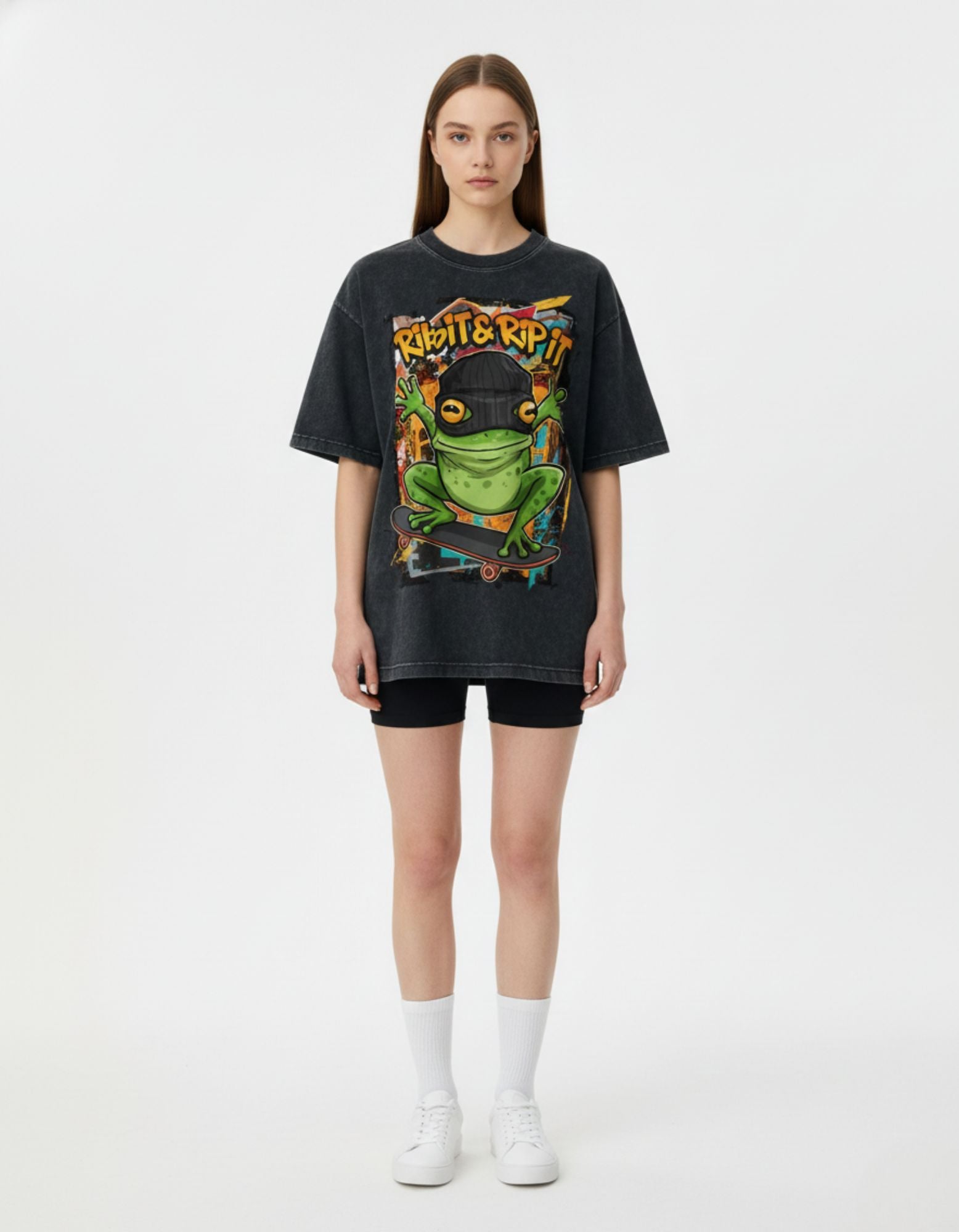 Female model wearing an oversized charcoal streetwear t-shirt with a frog graphic, styled with black biker shorts for a trendy look.