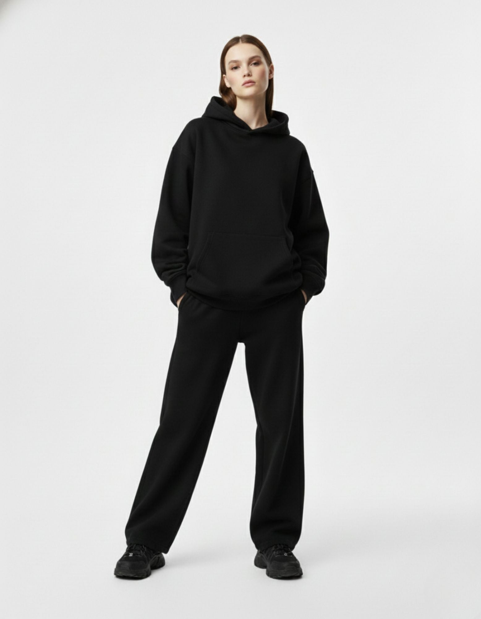 Front standing view of a female model in a plain black oversized streetwear hoodie with a relaxed, comfortable fit.