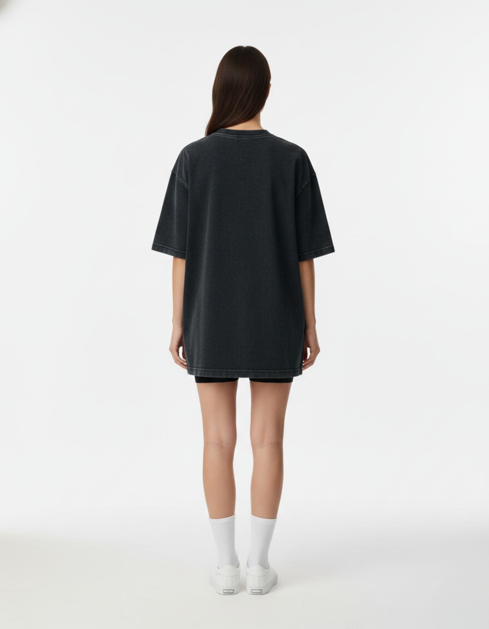 Rear view of the GENZs Fashion oversized vintage black streetwear t-shirt for women, styled with biker shorts.