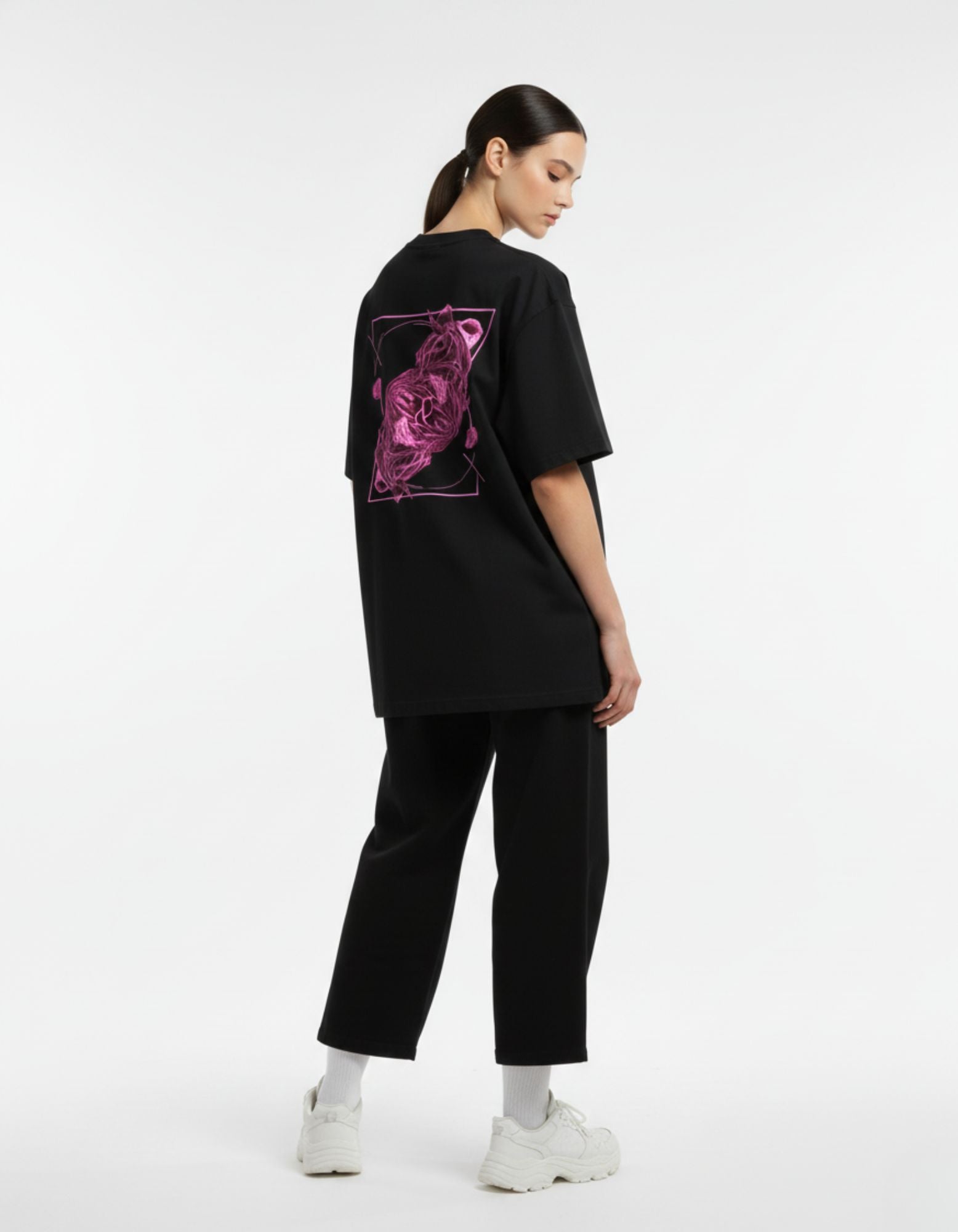 Back view of a female model in a GENZs Fashion black oversized tee with a signature pink abstract graphic.
