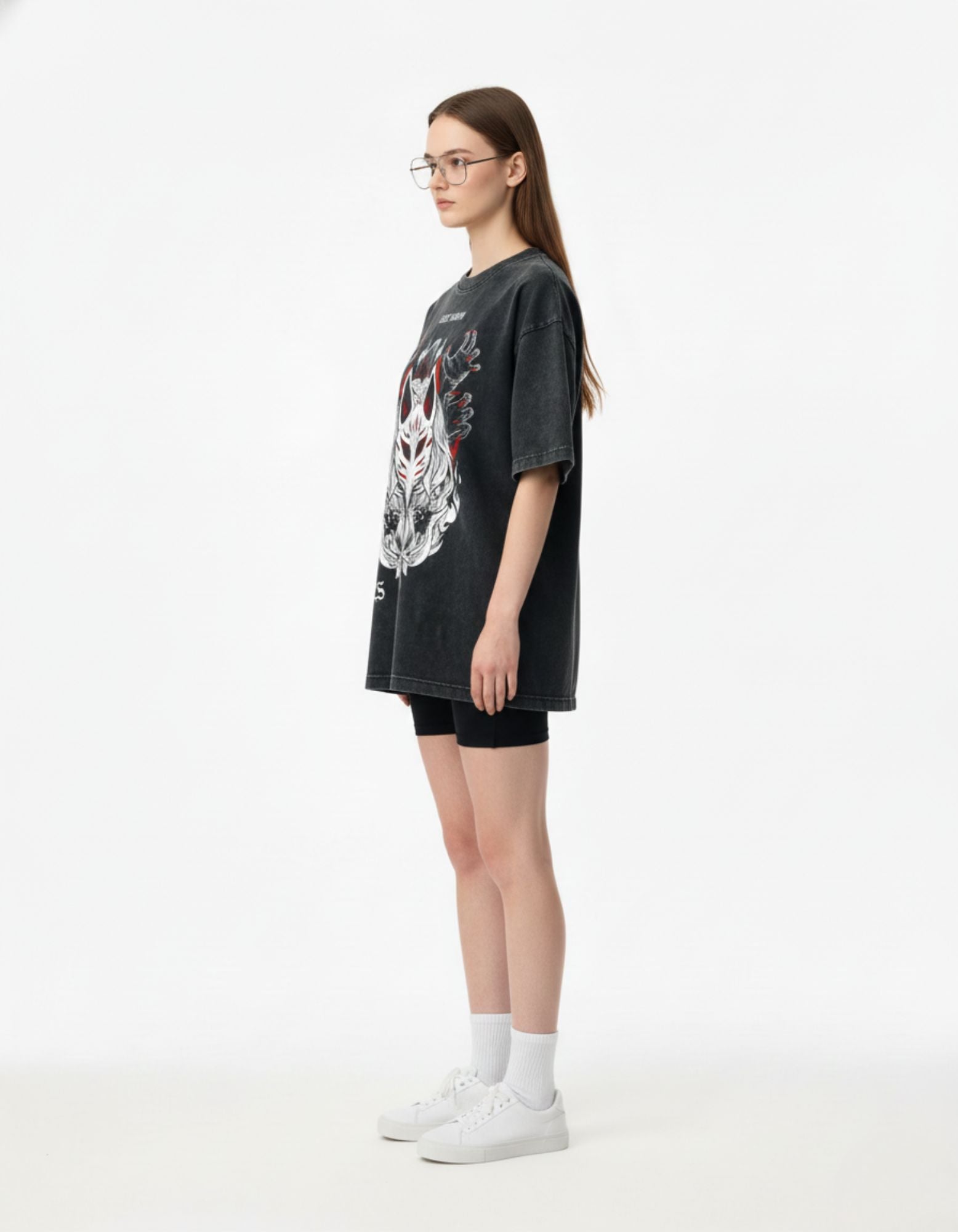 Person wearing a black oversized t-shirt with a graphic design on a white background