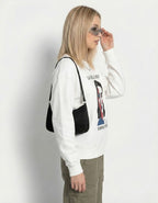 Side profile of a model wearing an oversized white art-inspired sweatshirt with olive cargo pants and a black shoulder bag.