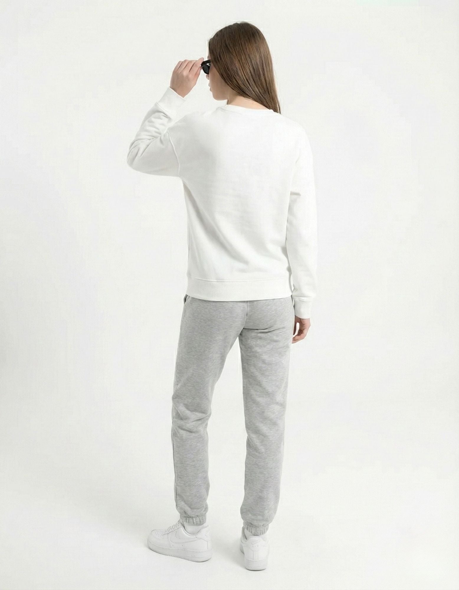 Side view of a female model wearing an oversized white anime sweatshirt with black sunglasses for a trendy urban look.