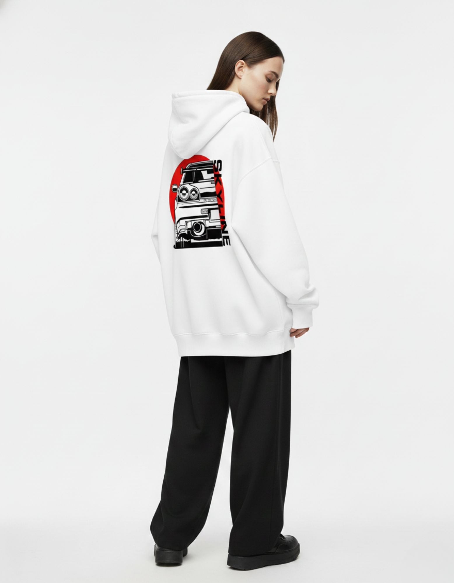 "Female model wearing a white oversized streetwear hoodie with a detailed Skyline car print on the back."