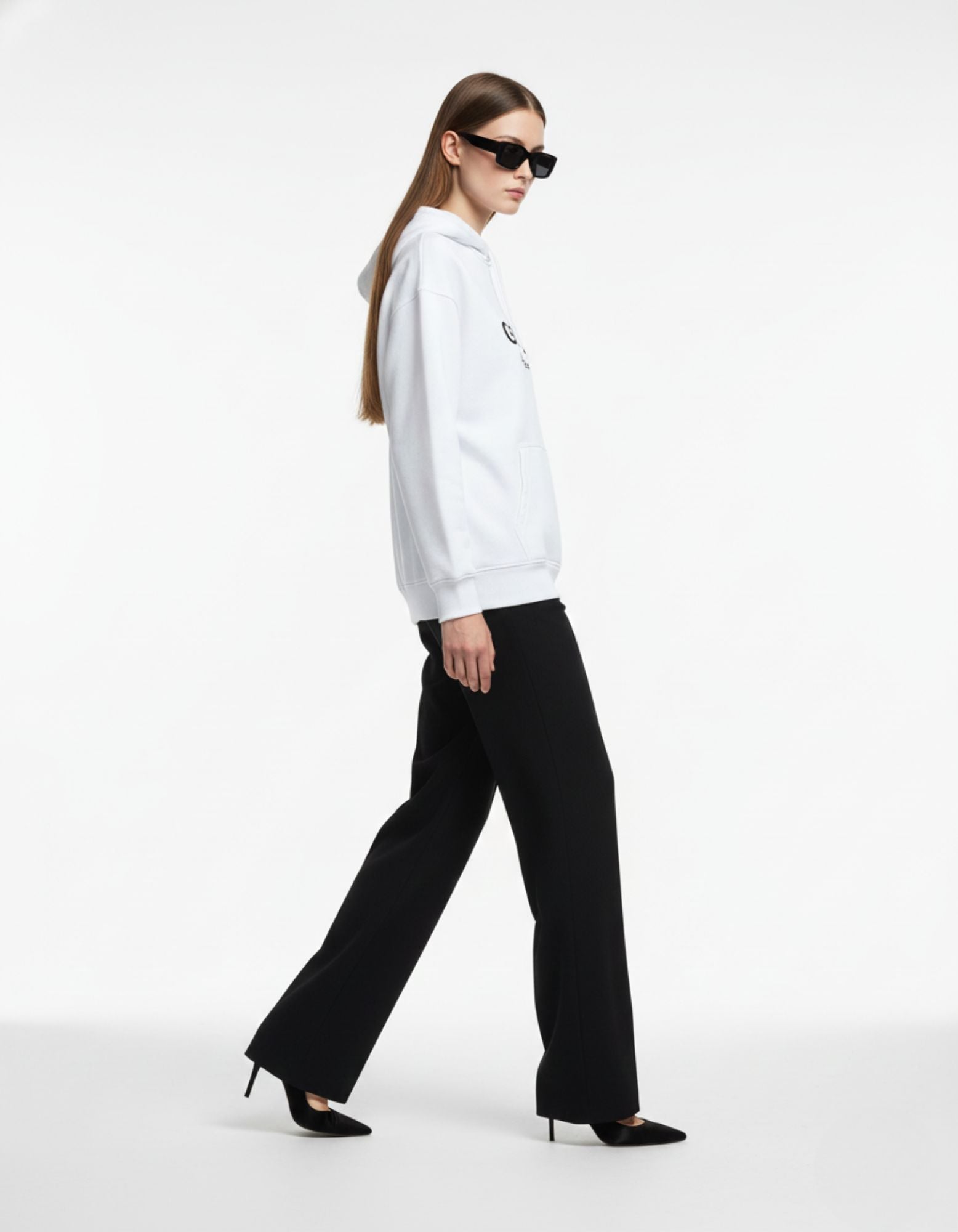 Side view of a woman wearing a GENZs Fashion white oversized hoodie styled with black wide-leg trousers and sunglasses.